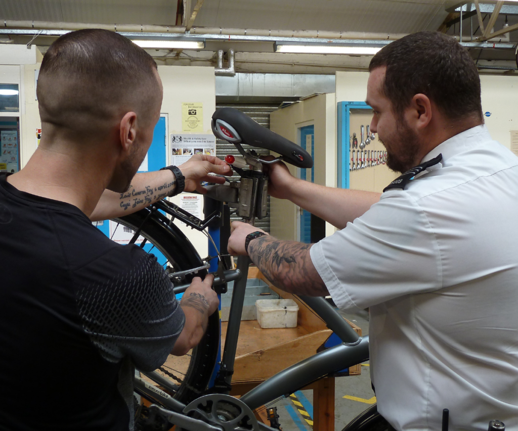 Headers Prison officer and participant fixing bike